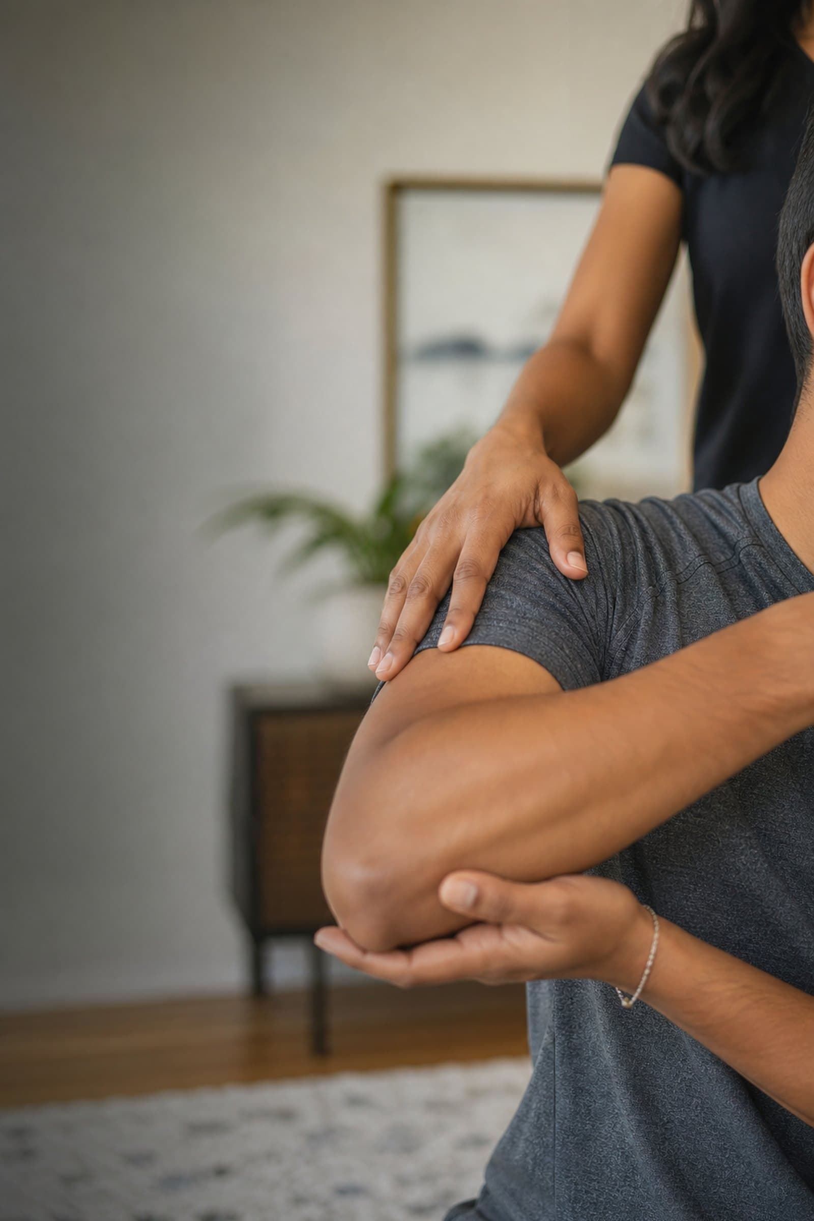 A physical therapist guiding a patient's shoulder during an in-home visit